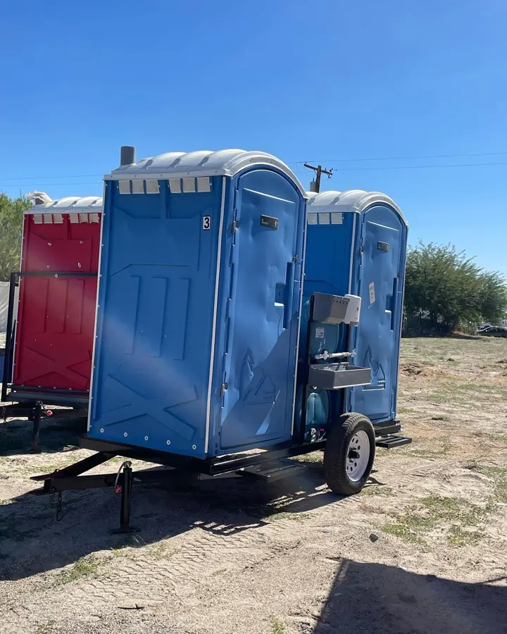 Blue porta potties with a sink mounted on a transport trailer
