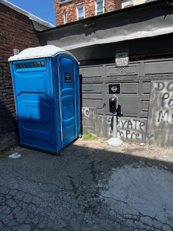 Blue standard porta potty placed in a commercial alley
