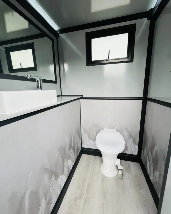 Restroom trailer stall with flushing toilet, vanity sink and window