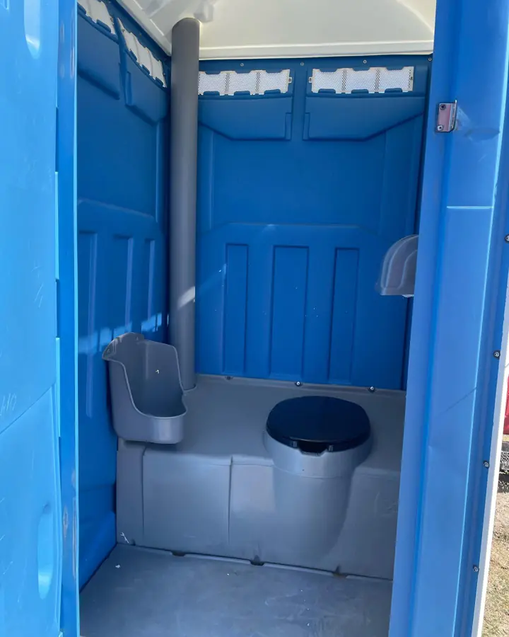 Clean standard porta potty interior with seat and dispenser
