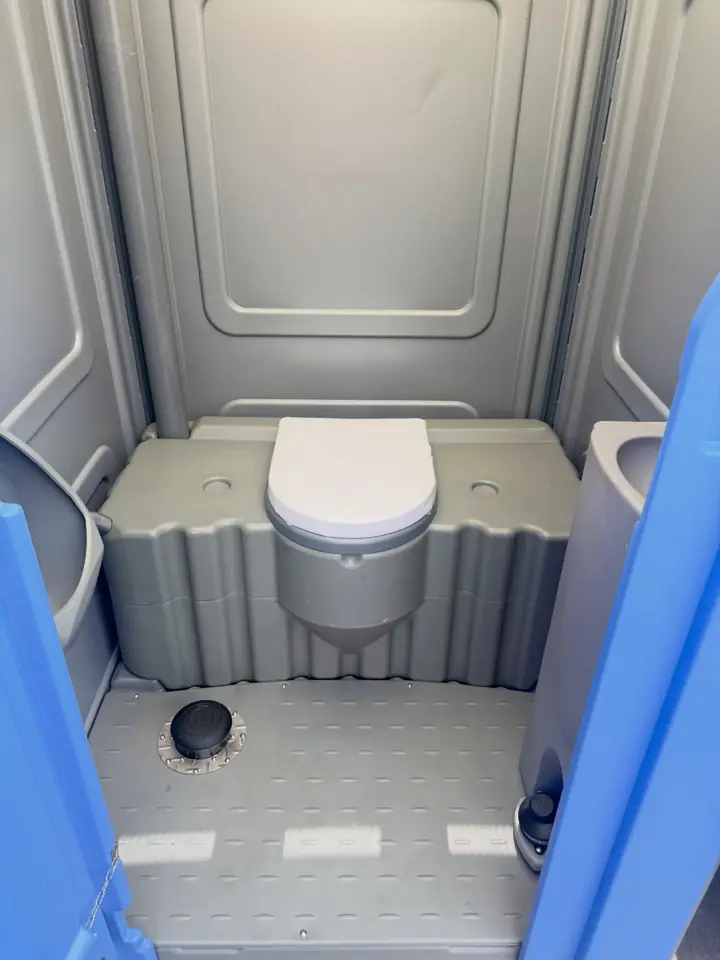 Grey standard porta potty interior with toilet seat and anti-slip floor