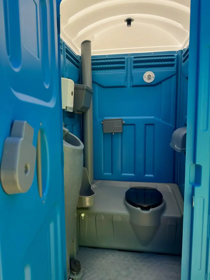 Interior of a standard porta potty with toilet seat, urinal and paper holder