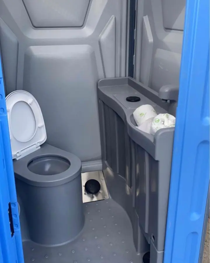 Standard unit interior with toilet seat and stocked toilet paper rolls